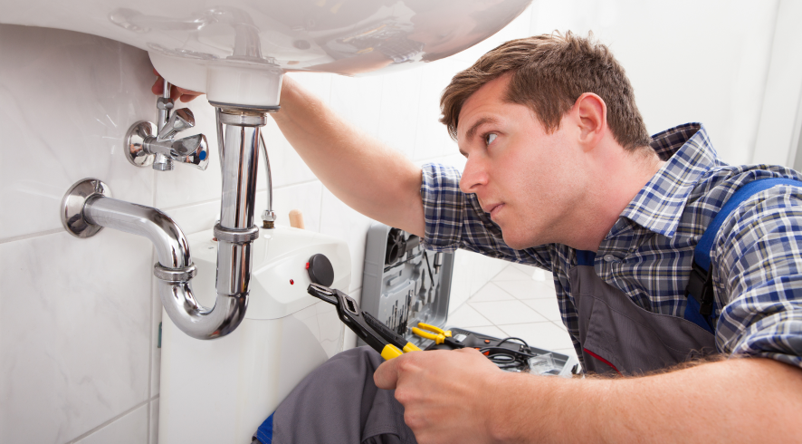 man with wrench under sink